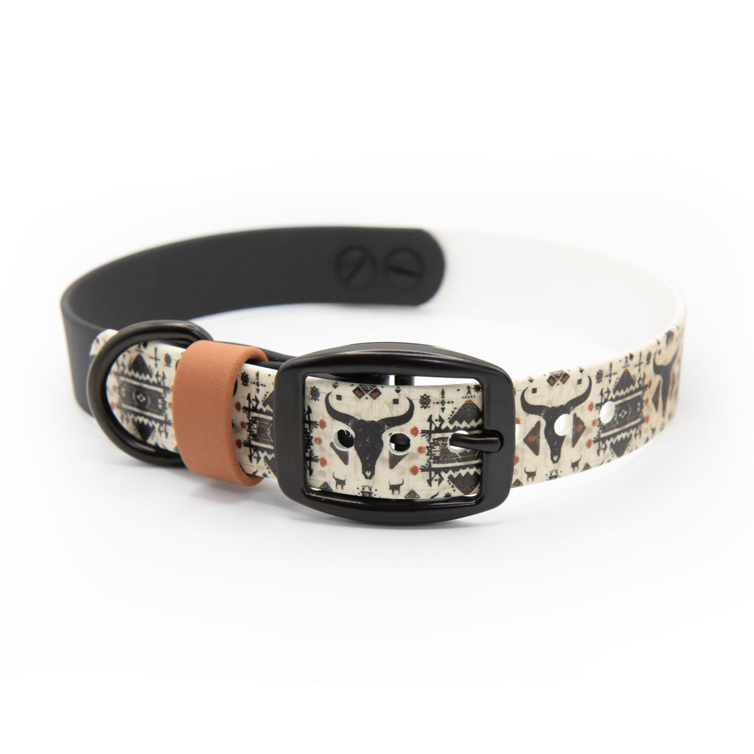 Dog collar with black buckle and waterned themed strap on a white background