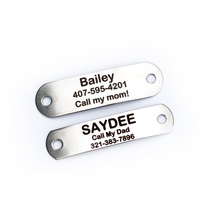 Two metallic tags with engraved names and phone numbers on a white background