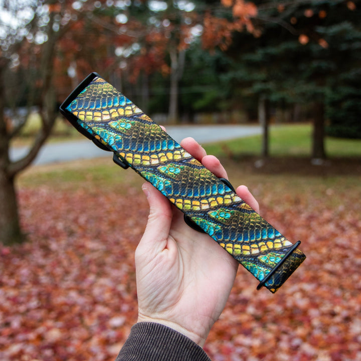 Hand holding a colorful patterned object with a blurred autumn background